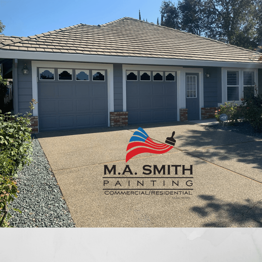Grey house with white trim and two garage doors, with M.A. Smith Painting logo.