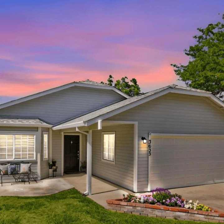 Single-story suburban home with light siding under a vibrant pink and purple sunset sky.